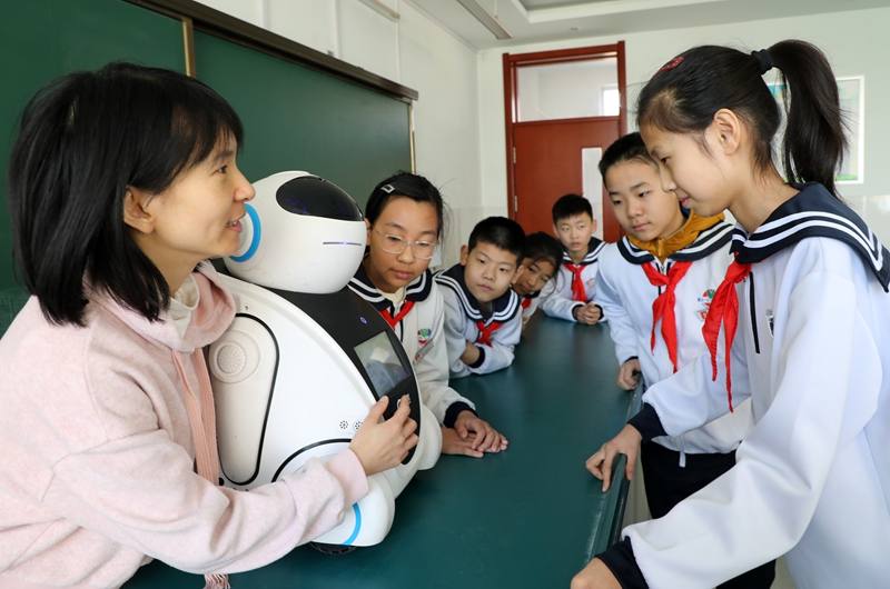 A teacher and primary school pupils in Shandong interact with a robot